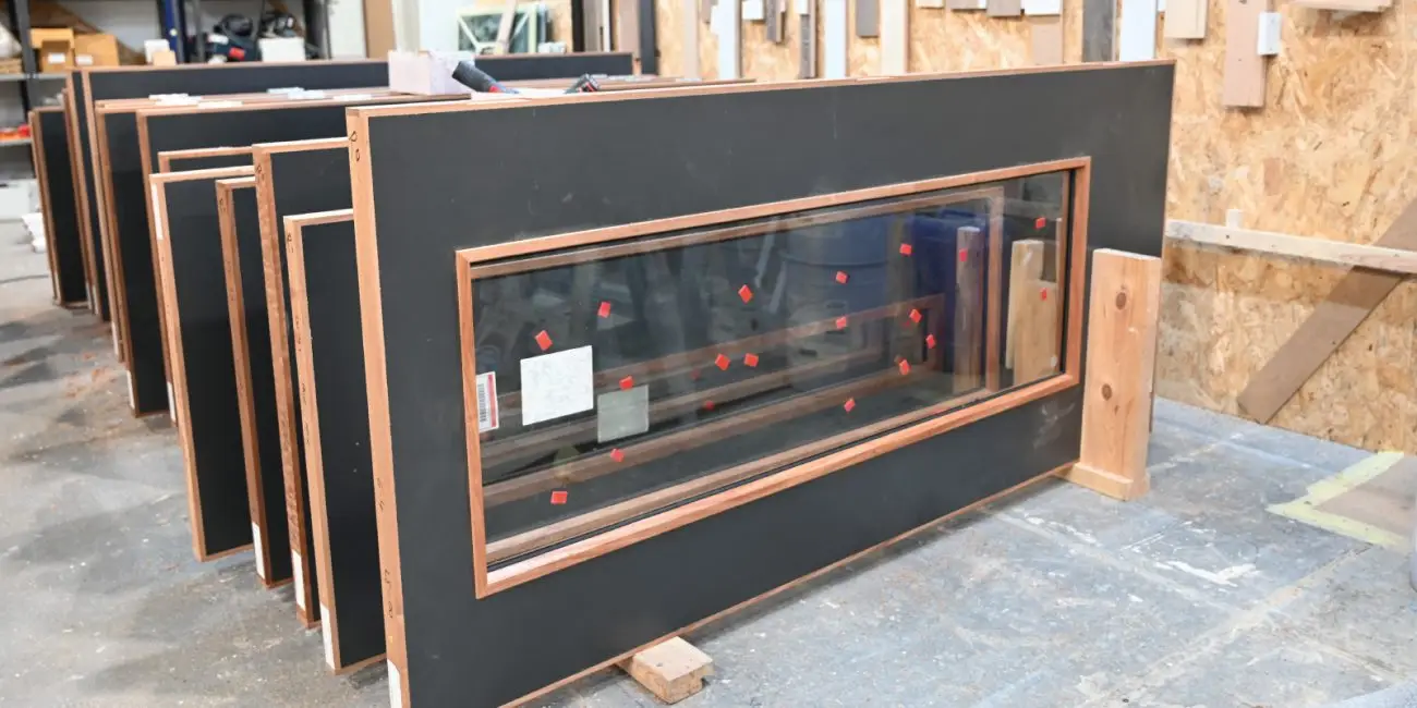 A row of doorsets in a manufacturing facility in Leeds with black doors with wooden frames.